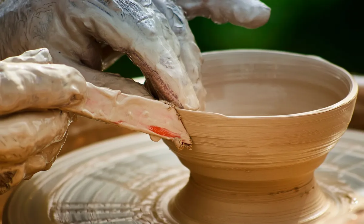 Hands shaping clay on a pottery wheel